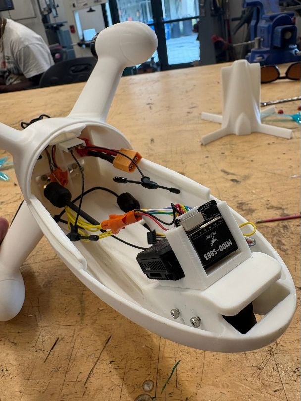 Open fuselage on a bench, with the flight controller, receiver and wiring fitted in white PLA